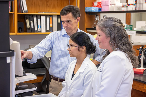 Three researchers looking at a computer screen.